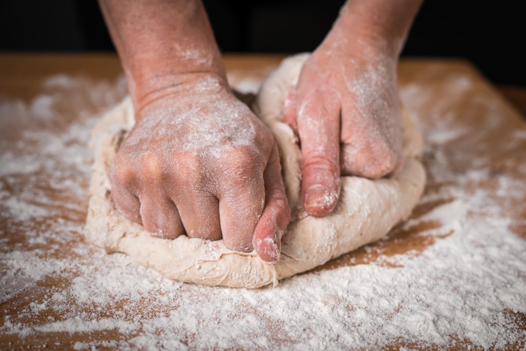 person kneading pizza dough