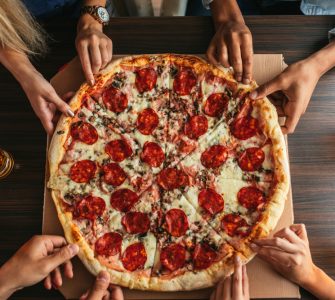 People's Hands Each Grabbing A Slice Of Pizza