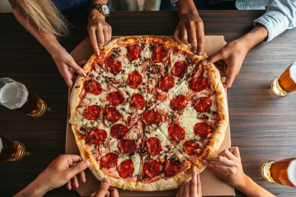 People's Hands Each Grabbing A Slice Of Pizza