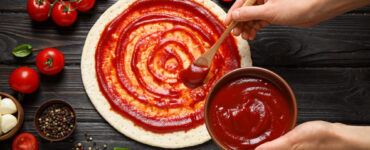 Spreading tomato sauce onto pizza crust